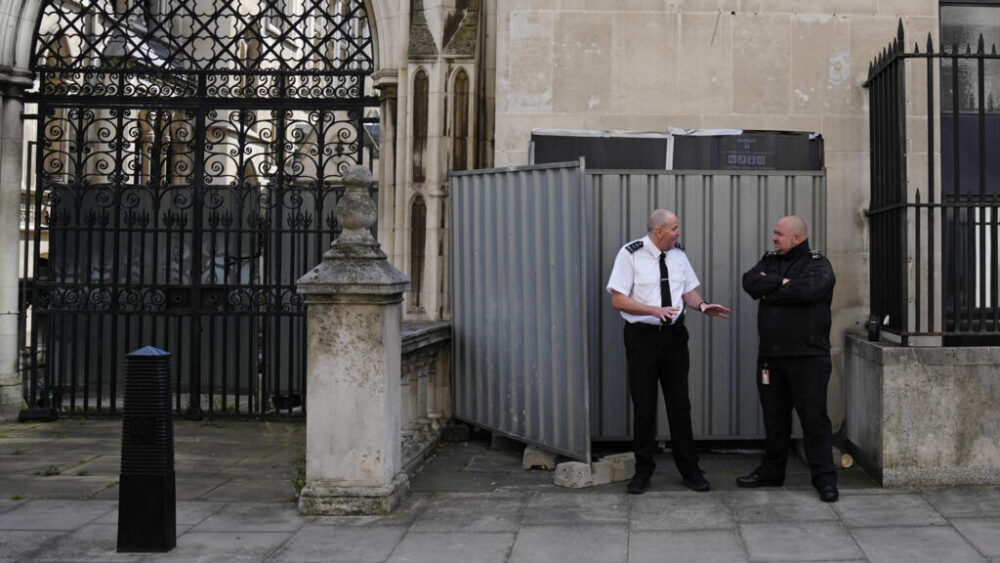 Agentes de seguridad montan guardia frente a las vallas que protegen la última obra de Banksy, que muestra a un juez amananzando a un manifestante con su mazo, aparecida el 8 de septiembre de 2025 en una pared de los Royal Courts of Justice, en Londres.