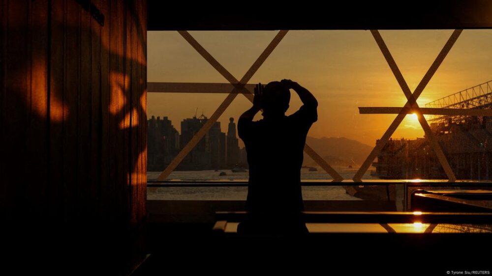 Un hombre protege con cinta los cristales de un ventanal al amanecer.