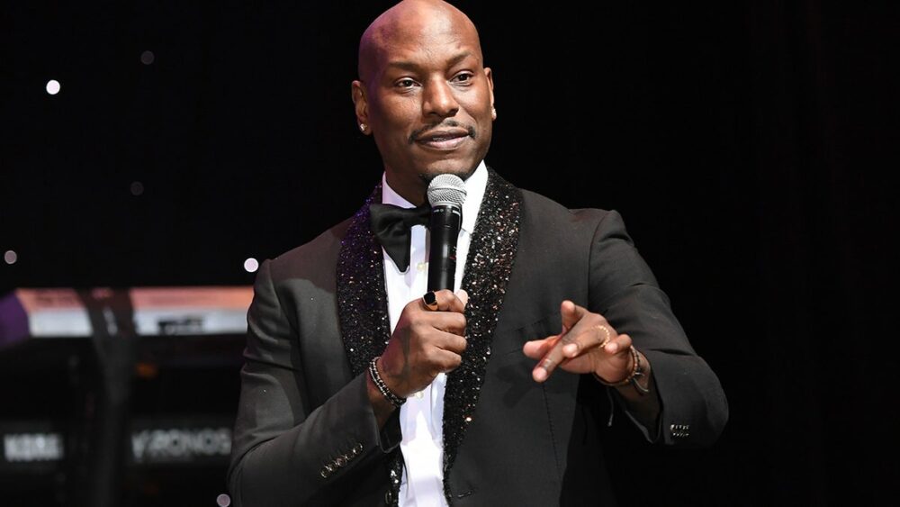 Tyrese Gibson sostiene un micrófono en el escenario.