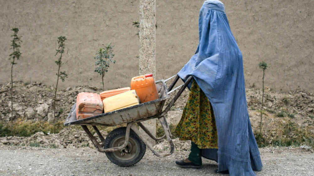 Una mujer afgana cubierta por un burka empuja un carrito con garrafas de agua vacías por una calle de Koshkak, en la provincia de Balj, el 5 de octubre de 2025 al norte de Afganistán