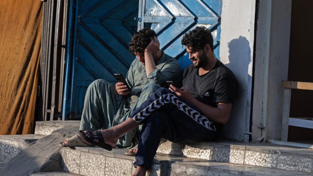 Dos afganos miran sus teléfonos móviles el 7 de octubre de 2025 en Kabul
