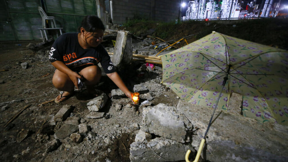 Un familiar de una víctima que falleció en el terremoto de magnitud 7,4 que golpeó a Filipinas coloca una vela en el lugar donde murió la víctima, en la localidad de Mati, provincia de Davao Oriental, en la isla de Mindanao