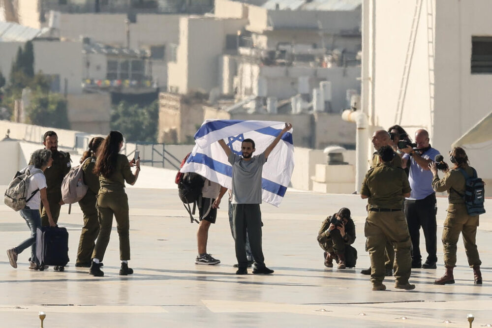 El israelí Nimrod Cohen, que fue rehén de Hamás en Gaza, ondea una bandera israelí en el helipuerto del centro médico Ichilov Sourasky de Tel Aviv, el 13 de octubre de 2025