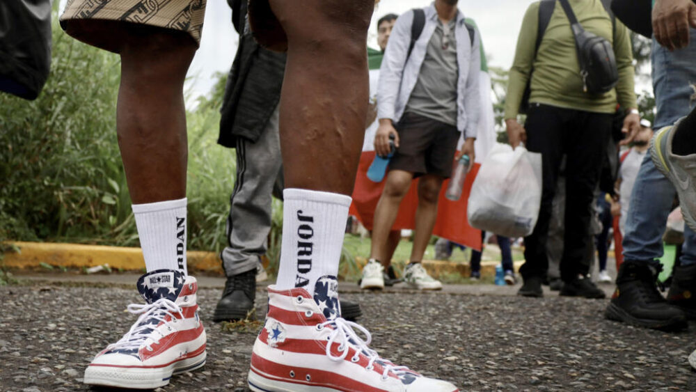 Un migrante con unas zapatillas con la bandera estadounidense marcha en una caravana de centenares de personas de diferentes nacionalidades de Tapachula a Ciudad de México, en busca de residencia legal para seguir camino a EEUU el 6 de agosto de 2025