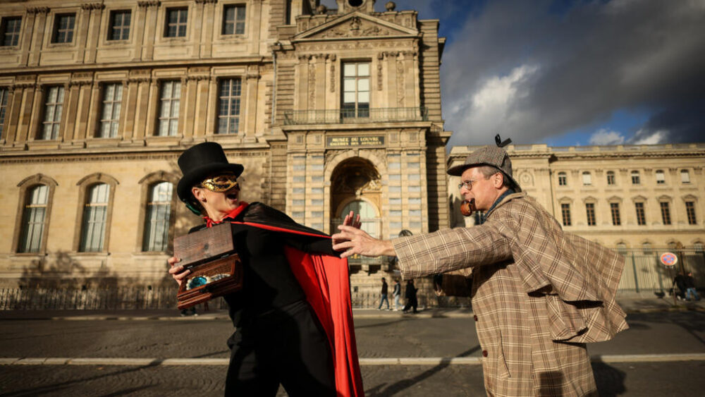 El robo de joyas se considera un humillante desastre de seguridad en Francia. Los miembros de la Sociedad Holmes de París (Cercle Holmesien de Paris), Laurence Deloision, vestida como Arsène Lupin, a la izquierda, y Thierry Gilibert, vestido como Sherlock Holmes, escenifican el robo junto a la fachada y la ventana desde donde los ladrones llevaron a cabo su atrevido golpe.