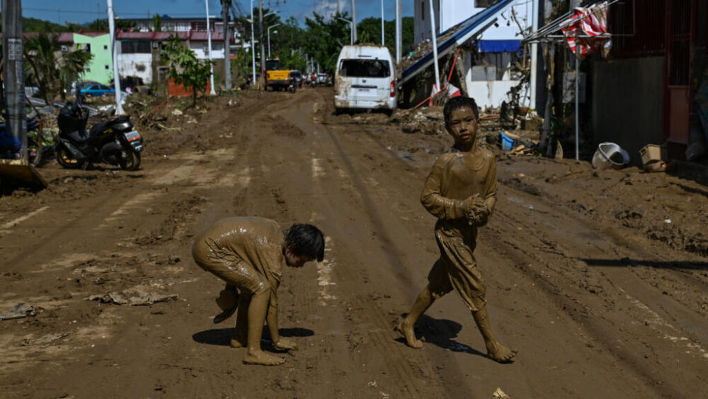Dos niños cubiertos de barro juegan en una calle tras el paso del tifón Kalmaegi en la ciudad de Liloan, en la provincia de Cebú, el 6 de noviembre de 2025 en el centro de Filipinas