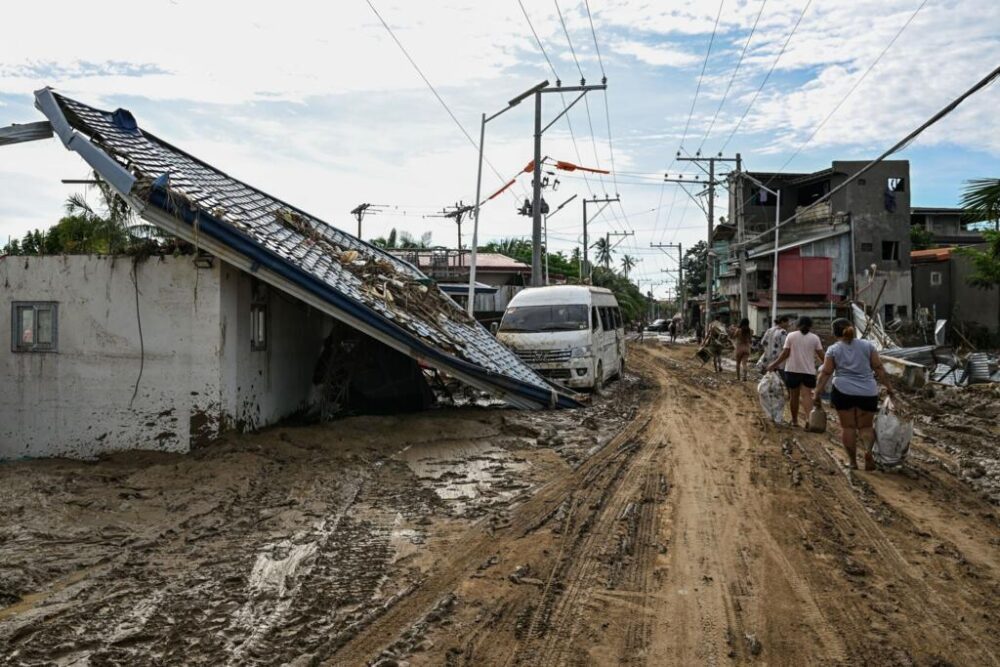 Los residentes caminan por una calle cubierta de barro tras el paso del tifón Kalmaegi en Liloan, Filipinas