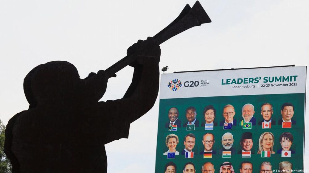 Perfil de una persona tocando un instrumento alargado de viento ante un cartel con los rostros de los mandatarios de los países que conforman el G20.
