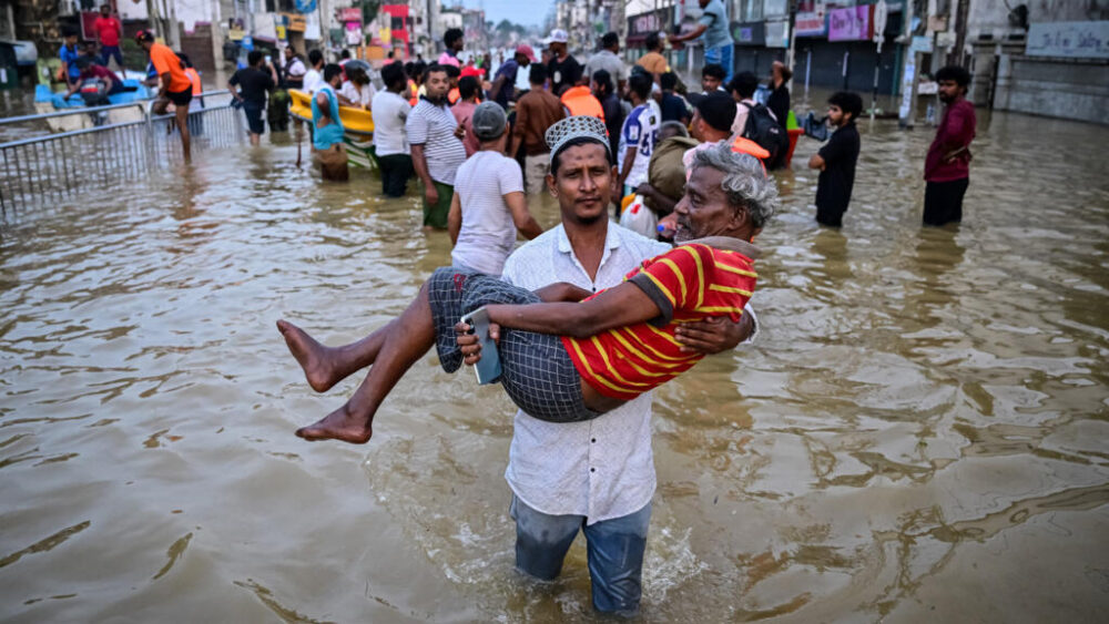 Un joven lleva a un anciano mientras atraviesan una calle inundada tras las fuertes lluvias caídas en las afueras de Colombo, el 30 de noviembre de 2025