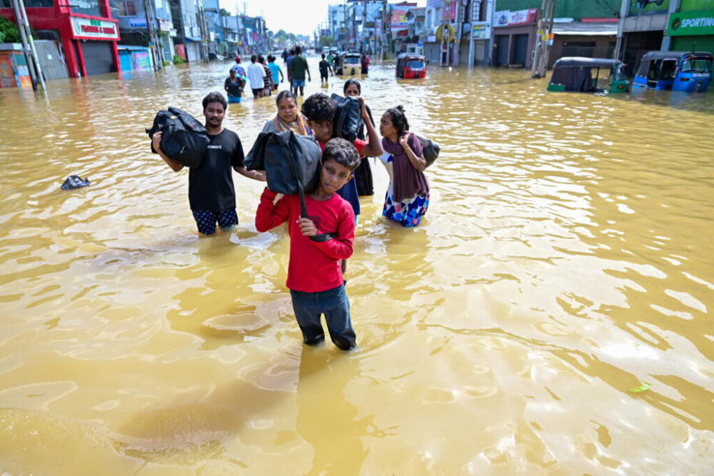 Habitantes llevan a cuestas sus pertenencias en una calle inundada en las afueras de Colombo, en Sri Lanka, el 30 de noviembre de 2025