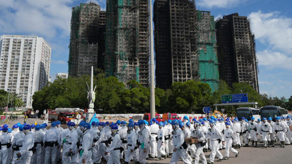 Agentes de policía vestidos con trajes protectores blancos frente a los bloques de viviendas de Wang Fuk Court tras el incendio, el 29 de noviembre de 2025 en Hong Kong