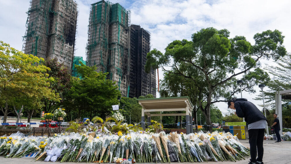 Personas ofrecen flores a las víctimas del incendio en la urbanización residencial del distrito de Tai Po, en Hong Kong, el lunes 1 de diciembre de 2025.