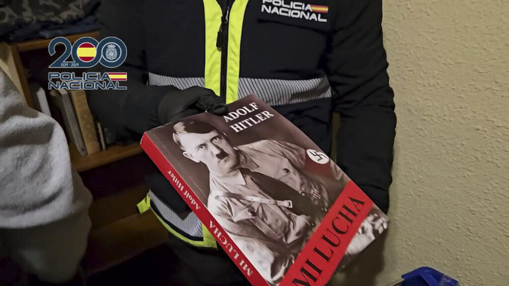 Un agente muestra un ejemplar de 'Mein Kampf', la obra de Adolf Hitler, hallado durante la operación contra los acusados de pertenecer al grupo neonazi The Base en la provincia de Castellón, al este de España, imagen tomada de un vídeo publicado el 1 de diciembre de 2025 por la Policía Nacional