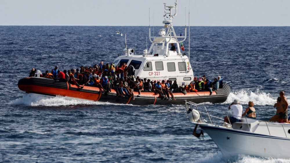 (Foto de archivo) Una embarcación de la Guardia Costera italiana que transporta a migrantes rescatados en el mar pasa cerca de un barco turístico, en la isla siciliana de Lampedusa, Italia, el 18 de septiembre de 2023.