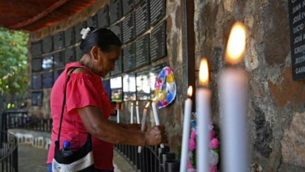 Una mujer enciende una vela en un monumento en homenaje a las víctimas de la masacre de El Mozote, en el marco de la guerra civil salvadoreña (1980-1992), el 7 de diciembre de 2019
