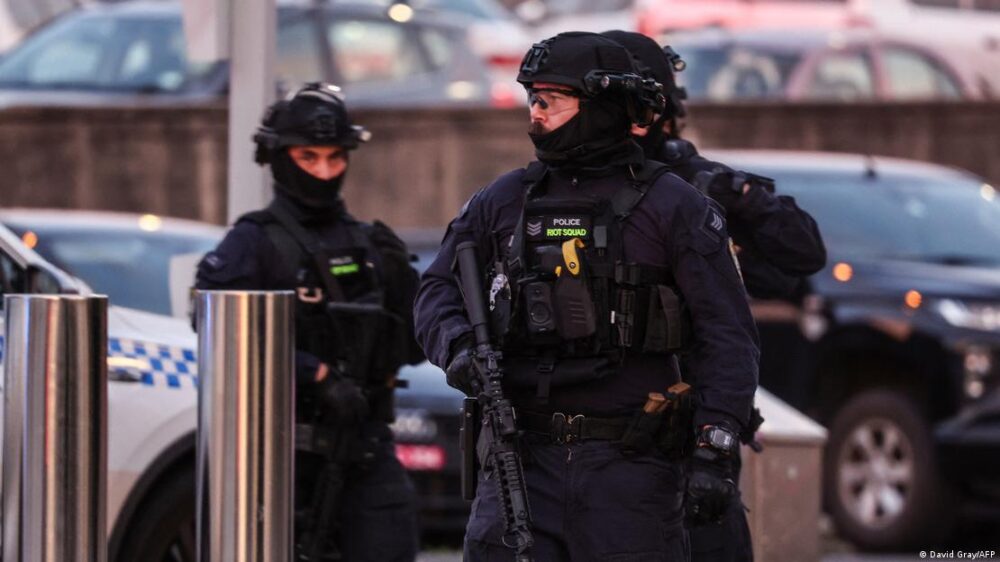 Tres agentes fuertemente armados junto a un vehículo policial. Tres agentes fuertemente armados junto a un vehículo policial.