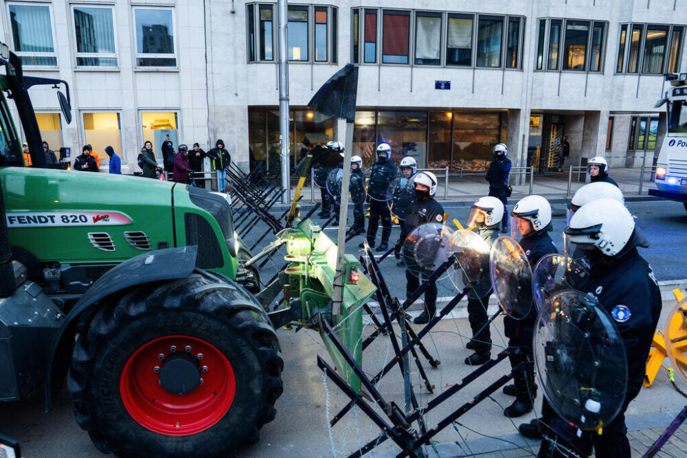 La policía vigila una barrera mientras los agricultores conducen sus tractores para bloquear una avenida principal durante una manifestación frente a una reunión de líderes europeos en la Cumbre de la UE en Bruselas, el jueves 18 de diciembre de 2025. (AP Photo/Marius Burgelman)