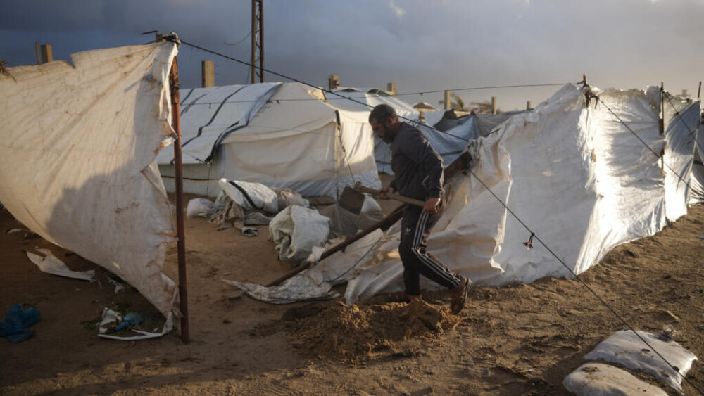 Un hombre intenta reforzar su tienda después de que fuera dañada por fuertes vientos, el 9 de enero de 2026 en Deir al Balah.