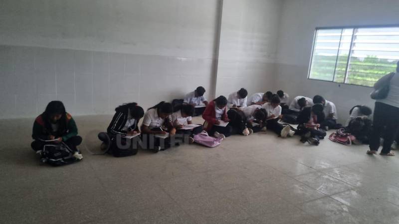 Los estudiantes toman apuntes apoyados en sus piernas Los estudiantes toman apuntes apoyados en sus piernas