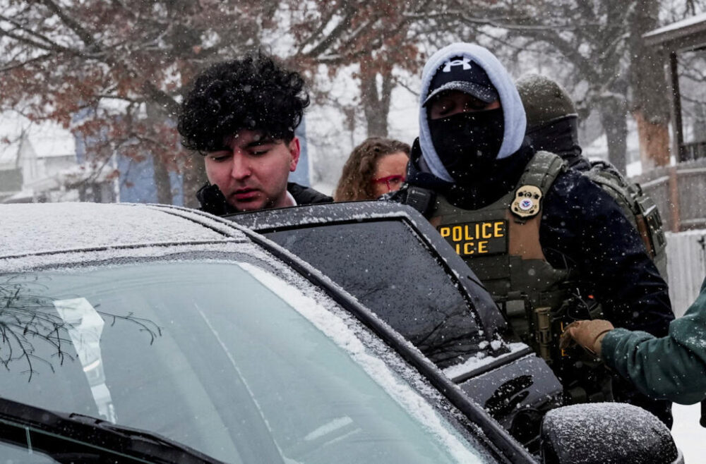 A man is led into a car after being detained by Immigration and Customs Enforcement (ICE) agents during an immigration raid, days after an ICE agent fatally shot Renee Nicole Good, in Minneapolis, Min