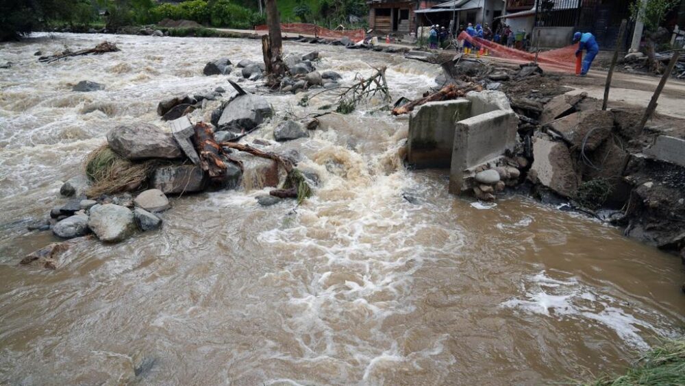 Trabajadores colocan una malla de seguridad para acordonar una carretera dañada por el desbordamiento del río Yanuncay en la zona de Barabón, en Cuenca, Ecuador, el 13 de marzo de 2026.