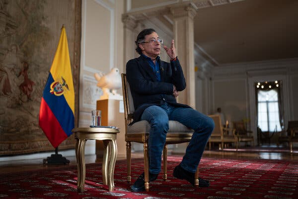 Un hombre con americana azul y vaqueros sentado en una silla de un despacho.