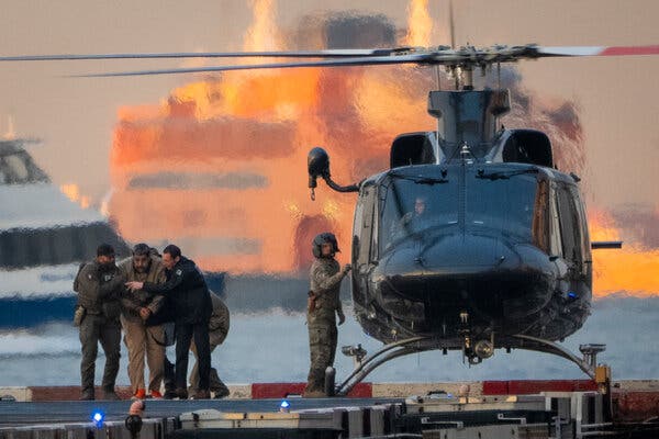 Un hombre es conducido fuera de un helicóptero negro en un helipuerto.