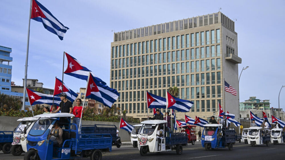 En bicicletas, motocicletas y triciclos eléctricos, los manifestantes recorrieron la avenida frente a la sede diplomática estadounidense portando banderas cubanas y carteles donde se leía: "Abajo el bloqueo".