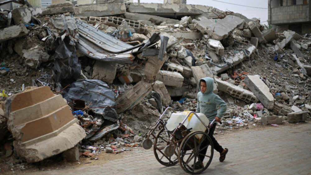 Un niño palestino desplazado empuja una silla de ruedas cargada con bidones llenos de agua en el campo de refugiados de Nuseirat, en el centro de la Franja de Gaza, el 1 de abril de 2026