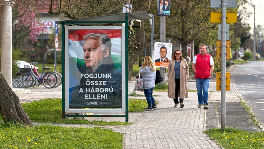 Unas personas pasan frente a un cartel electoral en el que aparecen el primer ministro húngaro, Viktor Orbán, y el lema «¡Unámonos contra la guerra!» en Albertirsa, Hungría, el jueves 9 de abril de 2026.