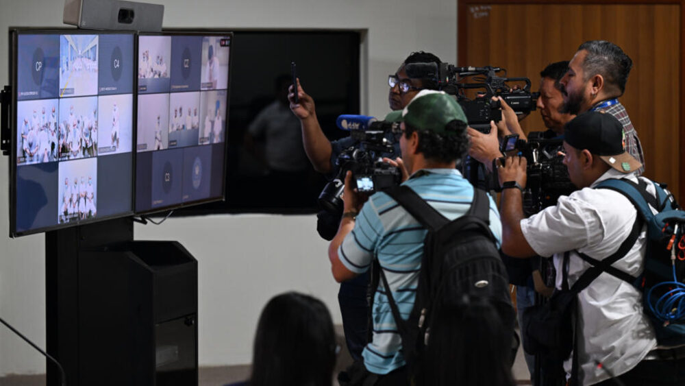 Unos fotoperiodistas documentan el juicio masivo contra pandilleros transmitido por videoconferencia en un centro judicial en Soyapango, en El Salvador, el 21 de abril de 2026