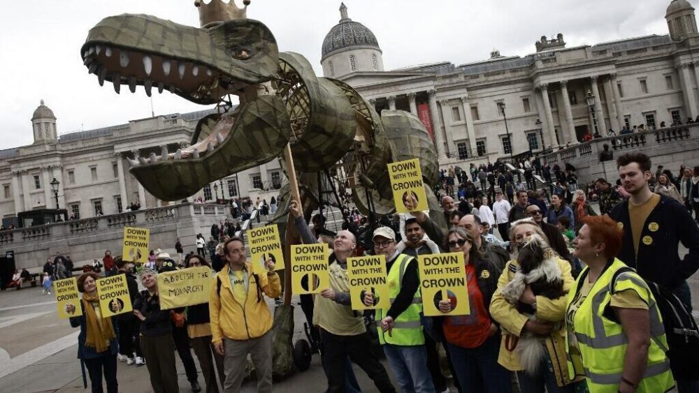 Una gran figura de un dinosaurio con una corona actúa junto a miembros del grupo antimonárquico «Republic» durante una protesta organizada en Trafalgar Square, en el centro de Londres, el 5 de mayo de 2024.