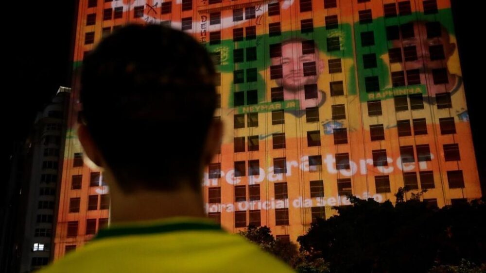 Un aficionado brasileño frente a la proyección del retrato de Neymar Jr. en un edificio de Río de Janeiro, el 18 de mayo de 2026, tras el anuncio de la convocatoria del delantero para la Copa Mundial de Fútbol de 2026.