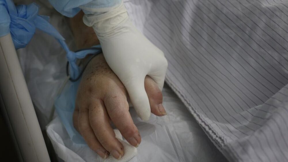 ARCHIVO. Una enfermera sostiene la mano de un paciente en una unidad de cuidados intensivos (Foto AP/Jorge Sáenz)