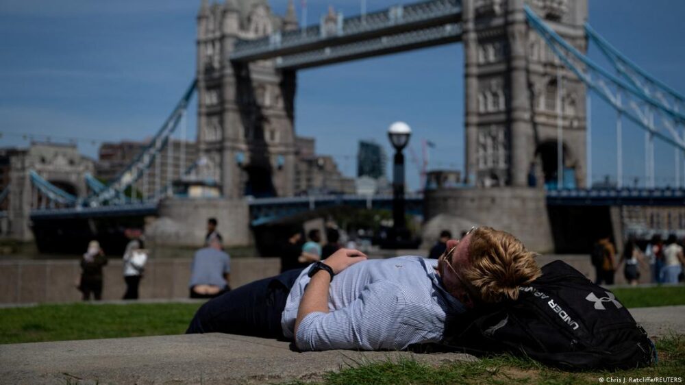 Un hombre recostado cerca del Tower Bridge en Londres durante la ola de calor. Un hombre recostado cerca del Tower Bridge en Londres durante la ola de calor.