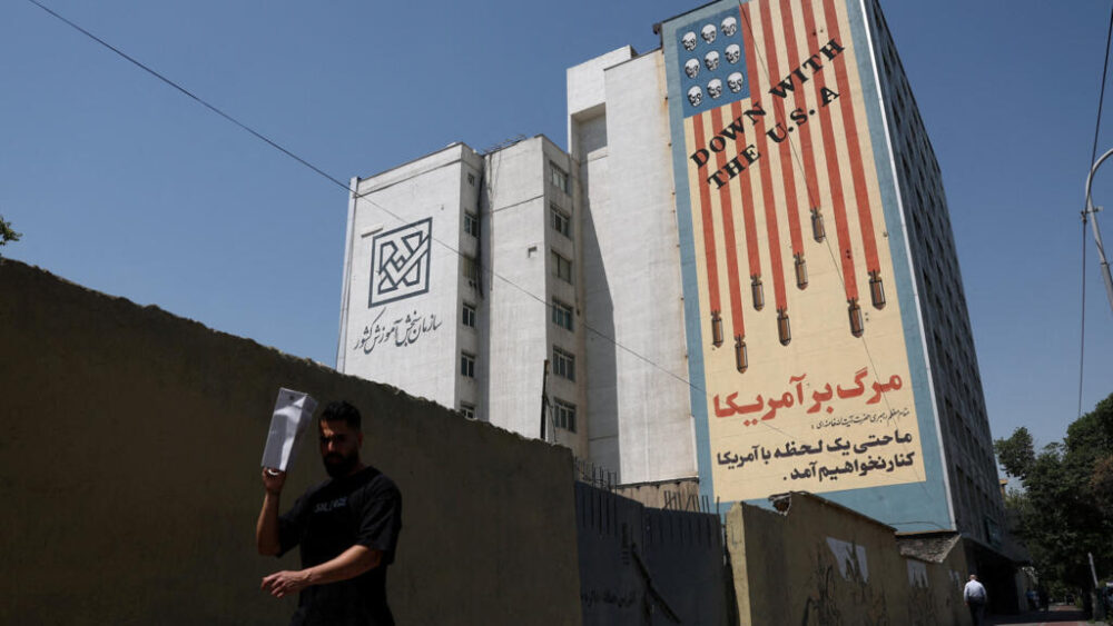 Un hombre pasa junto a un mural antiestadounidense en un edificio de Teherán, Irán, el 9 de junio de 2026.
