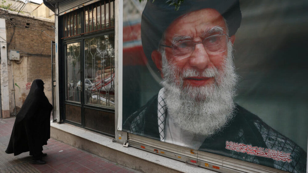 Una mujer pasa junto a una pancarta con una imagen del difunto líder supremo de Irán, el ayatolá Alí Jamenei, en una calle de Teherán, Irán, el 7 de junio de 2026. Majid Asgaripour/WANA (West Asia News Agency) vía REUTERS.